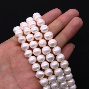 Macro di un filo di perle d'acqua dolce bianche tenuto da una modella su sfondo nero