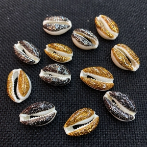 Macro detail of 12 natural cowrie shells with gold and black glitter for DIY jewelry making