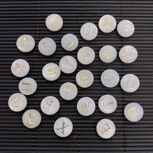 Detailed macro view of white mother of pearl shell beads with golden alphabet engraving