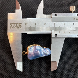 Macro view of blue baroque pearl pendant length measurement using a caliper tool