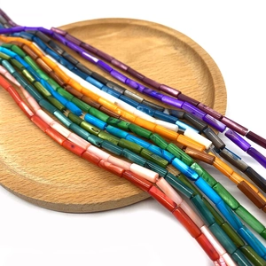 Gros plan de perles en coquillage cylindriques 4x13mm colorées avec texture marbrée