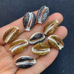 Close-up of DIY natural seashell beads with glitter gold and black finish held by hand