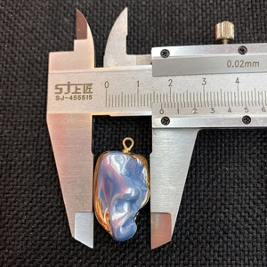 Detail shot measuring 14-15mm width of the organic shell pendant with gold plating