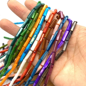 Gros plan de perles cylindriques en nacre teinte 4x13mm pour création de bijoux