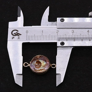 Detail van natuurlijke zoetwaterparel connector van 14 mm met gouden rand gemeten met schuifmaat