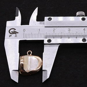 Measuring the 15mm natural shell tooth pendant with a digital caliper on black velvet