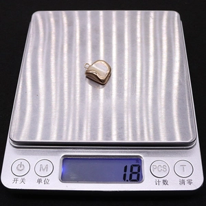 Macro shot of a 1.8g leaf-shaped shell pendant connector on a digital scale