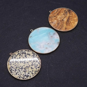 Detail view of 50mm round natural stone pendants with gold metal frames and hanging loops