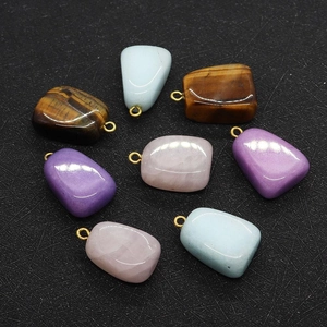 Detailed view of polished tiger eye and rose quartz irregular stone pendants for jewelry