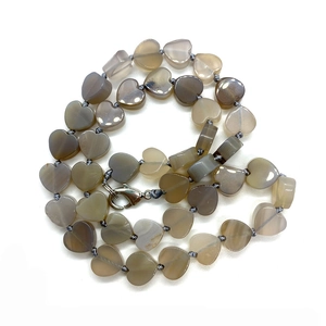 Dettaglio di perle in pietra naturale grigia a forma di cuore su collana annodata