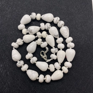 Macro shot of white turquoise teardrop and disc beads with a silver lobster clasp