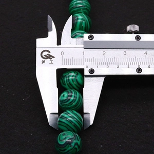 Makroaufnahme von 10mm Malachitperlen mit grünen Streifen und digitalem Messschieber