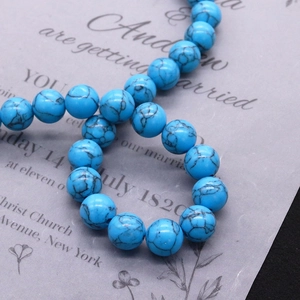 Primer plano de cuentas de turquesa sintética azul con vetas naturales para joyería