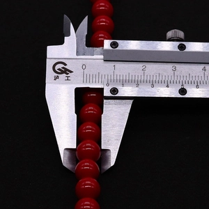 Primer plano de un calibre digital midiendo una cuenta roja de 8mm para crear joyería