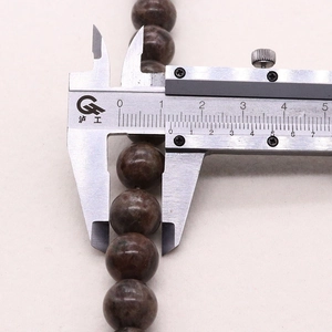 Macro view of measuring 10mm natural coffee gemstone round beads with a caliper