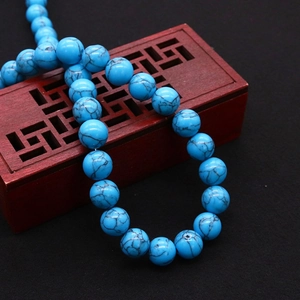 Collar de cuentas de turquesa azul sintética sobre un joyero de madera tallada