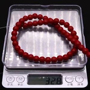 Detailed view of red round gemstone beads on a digital scale showing 32.8g weight