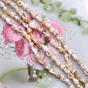 Natural long spiral shell beads for DIY jewelry making on a floral background