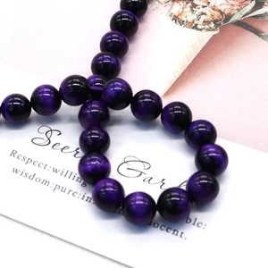 Polished natural purple tiger eye stone beads for DIY jewelry making on white background