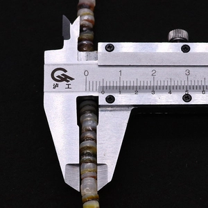 Macro detail of 8mm natural shell beads measured with a digital caliper for DIY jewelry