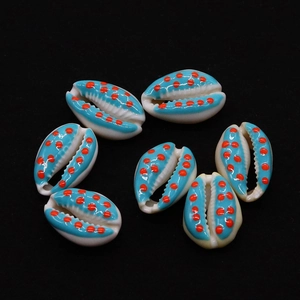 Macro detail of hand-painted blue and orange polka dot natural cowrie shell pendants
