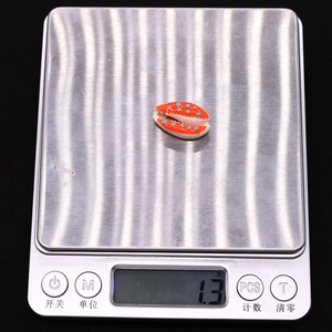 Detail showing shell-shaped bead weight of 1.3 grams on a digital electronic scale