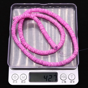 Close-up of pink shell disc heishi beads on an electronic scale showing 42.7g weight
