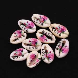 Macro view of ten natural cowrie shells with floral prints and LOVE text for DIY jewelry