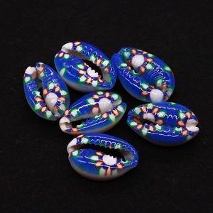 Close-up of six vibrant blue cowrie shell beads with colorful floral print for DIY jewelry