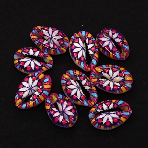 Macro shot of colorful painted cowrie shell beads with geometric floral patterns for DIY jewelry