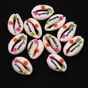 Macro detail of natural seashell beads with hand-painted flowers and 'dream' lettering