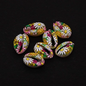 Macro detail of natural shell beads with colorful daisy prints for DIY jewelry making