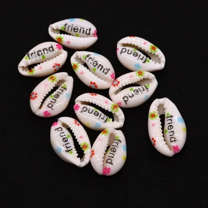 Macro detail of natural shell beads with friend text and floral patterns for DIY jewelry