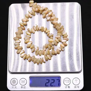 Vista dettagliata di perle in conchiglia naturale del peso di 22,7 g su una bilancia