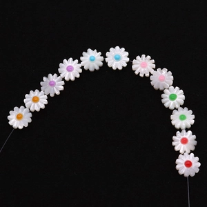 Makro-Detail von weißen Muschel-Gänseblümchen-Perlen mit bunten Mitten für DIY-Schmuck