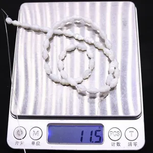 Macro shot of natural spiral seashell beads on weighing scale showing weight of 11.5g