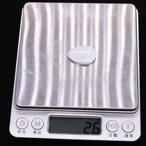 Macro view of a 2.6g teardrop shaped white mother of pearl bead on a digital scale