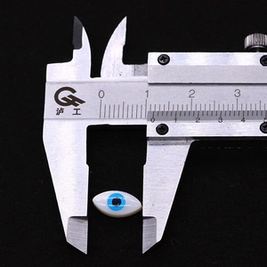 Macro shot of 12.5mm evil eye shell bead being measured with a digital caliper