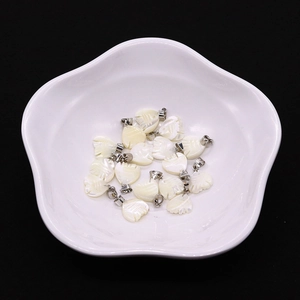 Ciondoli a forma di pesce in conchiglia naturale con anelli in metallo su piatto bianco