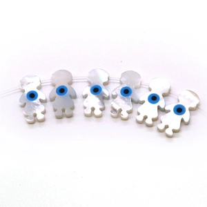 Macro detail of doll-shaped seashell beads featuring blue evil eye patterns for DIY jewelry