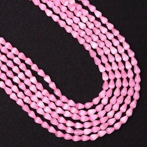 Detalle macro de cuentas facetadas de gota rosa con efecto ojo de gato para joyas