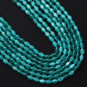 Macro-opname van ovale kattenoogkralen in meergrün met glinsterend effect voor DIY-sieraden