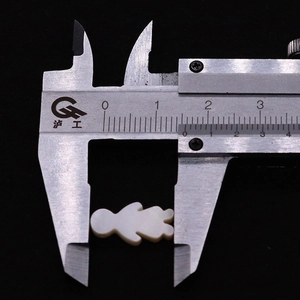 Makroaufnahme einer 12mm Naturmuschel-Mädchenperle, die mit einem Messschieber gemessen wird