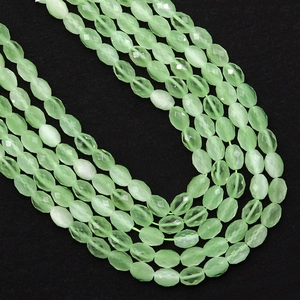 Macro-opname van gefacetteerde ovale lichtgroene kattenoogkralen voor sieraden