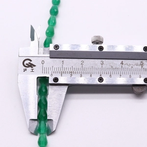 Macro shot of 8.5mm green faceted teardrop cat-eye stone beads for jewelry making