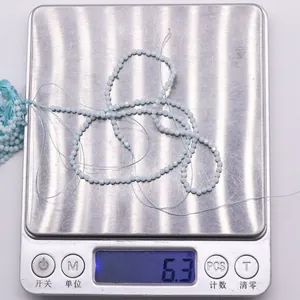 Detailed close-up of light blue faceted beads on a scale showing 6.3 grams weight