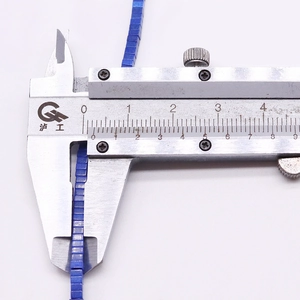 Macro shot measuring 2mm square blue synthetic turquoise stone beads with a caliper