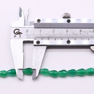Macro shot of 8mm green faceted teardrop cat eye stone bead measured with a caliper