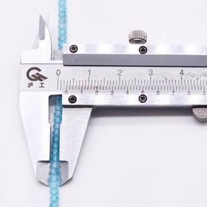 Macro shot of 2mm sky blue faceted natural stone beads measured with a caliper tool