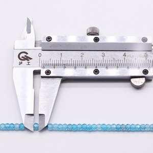 Macro shot of 2mm faceted sea blue natural stone beads with caliper for size reference